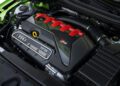 Close-up view of an Audi RS5 engine bay featuring the TFSI engine with red and carbon fiber accents, visible Audi badge, and various components—celebrating the 50th anniversary of the iconic Audi five-cylinder engine.