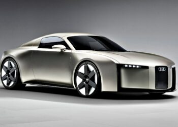 A silver Audi concept car from 2025 with a sleek, futuristic design, angular lines, narrow headlights, and large black-and-silver wheels is showcased in a studio setting.