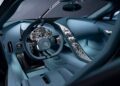 The Bugatti Tourbillon interior of this hypercar features a round steering wheel, multiple analog dials, metallic controls, and blue leather upholstery that’s designed to age gracefully.