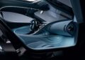 View of a modern luxury hypercar interior focusing on the dashboard, steering wheel, and front passenger seat, featuring sleek blue and metallic design elements reminiscent of a Bugatti Tourbillon.
