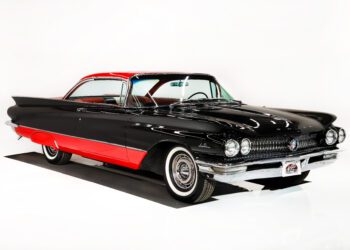 A vintage black and red two-door car with whitewall tires is displayed in a white studio setting, capturing the timeless allure of a Hollywood Classic.