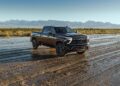 A black Chevrolet Silverado pickup truck from the ultra-exclusive Stars & Steel Collection is parked on a wet, muddy plain with mountains in the background under a clear sky, as Chevy honors America’s 250th anniversary.