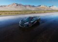 A black sports car from the Chevy Honors America’s 250th Anniversary With Ultra-Exclusive Stars & Steel Collection is parked on an empty, wet road with mountains and a clear sky in the background.