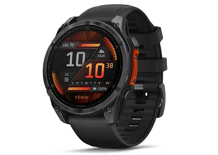 A black Garmin Fenix smartwatch with an orange-accented digital display—featured in the duPont REGISTRY 2026 Holiday Gift Guide—shows the time, date, steps, and battery level.