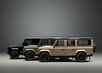 Three Land Rover Defender vehicles—including a Classic Defender and a Defender OCTA—in black, green, and beige are parked side by side in a studio setting with a neutral gray background.