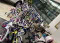 A row of children's bicycles, toys, and gift bags are displayed indoors near a decorated Christmas tree and a parked white vehicle at the Dimmitt Automotive Group's Toys for Tots event.