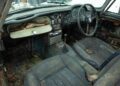 The interior of a rare car, possibly an Aston Martin DB5, shows worn leather seats, a damaged dashboard, and visible rust and mold.