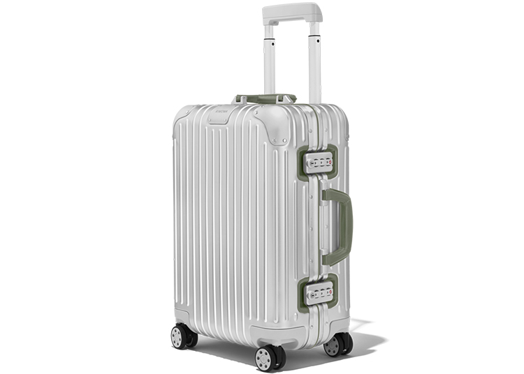 A white hard-shell suitcase with ribbed texture, green handles, and four wheels is shown with its telescoping handle extended—a stylish pick for your 2026 Holiday Gift Guide from duPont REGISTRY.