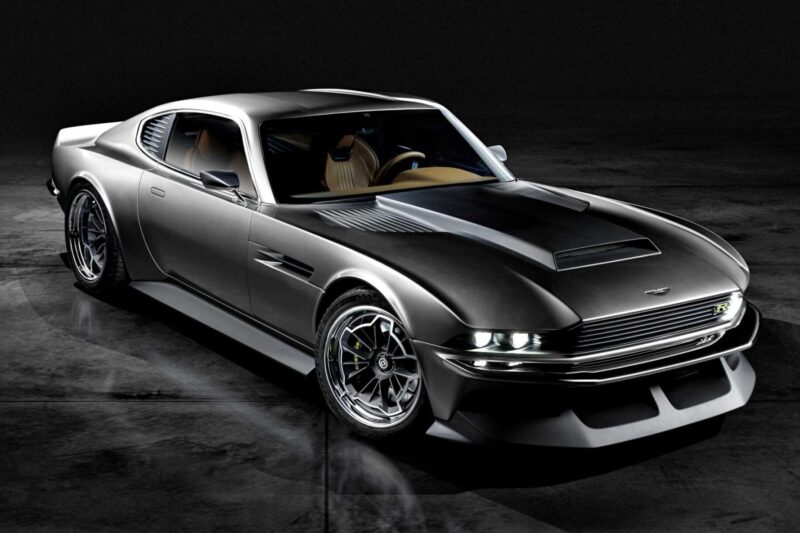 A sleek, metallic grey sports car with a classic coupe design—featured in "20 Cars That Focused on Analog Engagement in 2025"—is parked on a dark, reflective surface under low lighting.