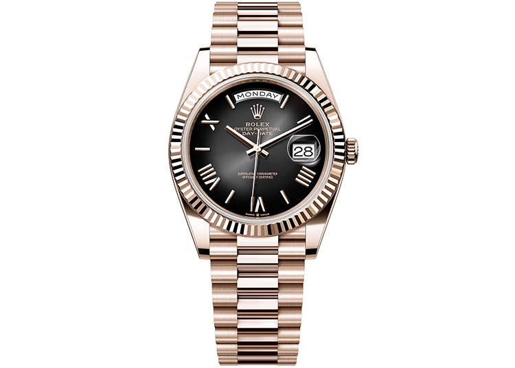 A rose gold Rolex wristwatch with a black dial, Roman numerals, and a date and day display—an elegant choice featured in the duPont REGISTRY 2026 Holiday Gift Guide.