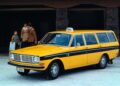 A yellow Volvo V60 Cross Country taxi with a roof sign is parked on a snowy surface as two adults and a child stand in the background near a building entrance, capturing the spirit of the wagon era before final U.S. orders.