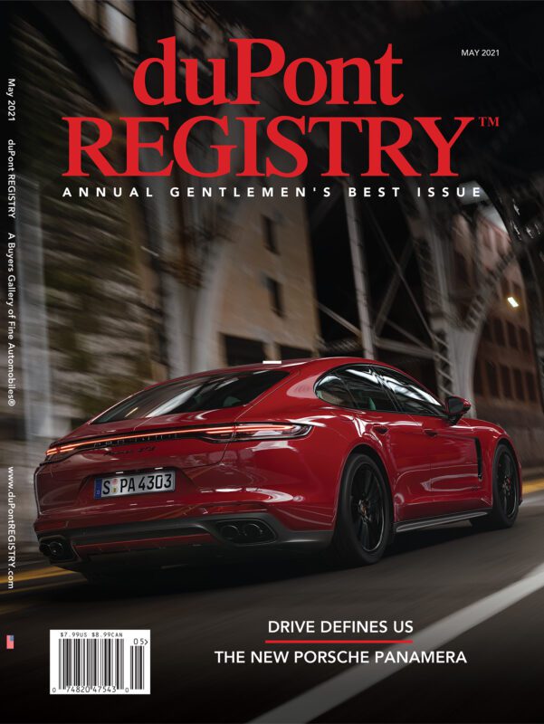 A red Porsche Panamera drives through a city street at dusk, featured as one of the Cover Cars on the May 2021 duPont REGISTRY magazine for its 40th Anniversary.