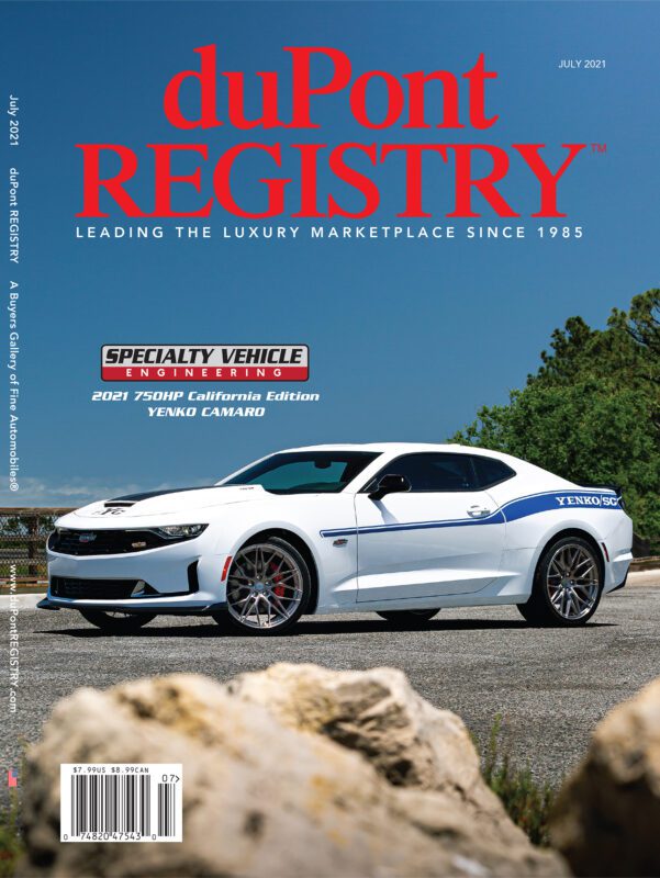A white Yenko Camaro with blue stripes is parked on a paved surface, featured as one of the Cover Cars for the July 2021 issue of duPont REGISTRY, celebrating its 40th Anniversary.