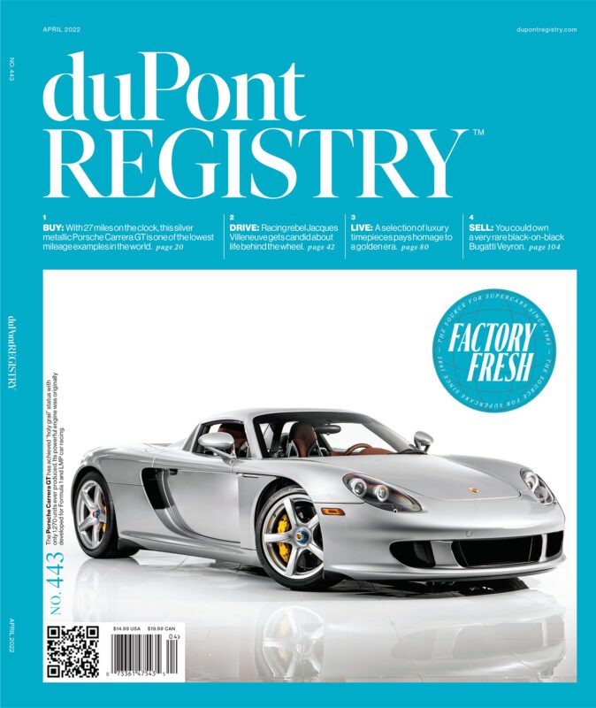 A silver Porsche Carrera GT convertible shines on the duPont REGISTRY's April 2022 issue, celebrating 40th Anniversary Cover Cars against a striking blue background and showcasing various feature highlights.