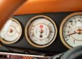 Close-up of three vintage-style car dashboard gauges, displaying temperature, pressure, and RPM readings with gold accents on a black and tan panel.