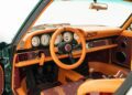 Classic car interior featuring a retro-style dashboard with analog gauges, orange and brown upholstery, and a three-spoke steering wheel.