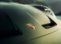 Close-up of a green Porsche hood featuring the Porsche logo, with partial headlight and outdoor background visible—a fitting tribute to Porsche 90th Birthday.