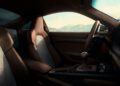 Interior of a Porsche 911 GT3 with brown leather seats, manual gear shift, and houndstooth seat inserts, celebrating F. A. Porsche’s legacy—mountains visible through the window on his 90th birthday.