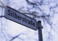 A street sign reads "Silberstraße" in German, with blurred tree branches and sky in the background—an inviting scene on the road to Christmas.