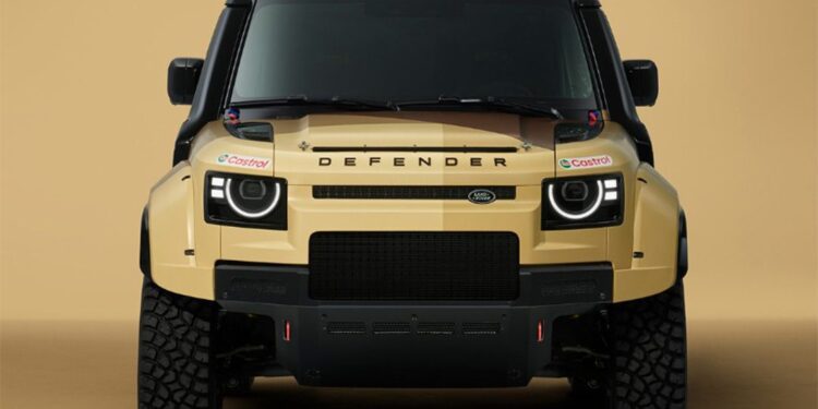 Front view of a tan Land Rover Defender with rugged tires, black accents, a green roof, and Castrol sponsor stickers, set against a beige background.